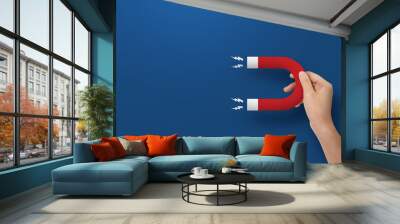 Close up of hand holding horseshoe magnet at blue background. Wall mural