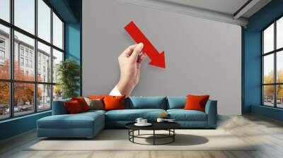 Woman holding red graph chart arrow that is pointing down at grey background. Concept of Global Recession. Wall mural