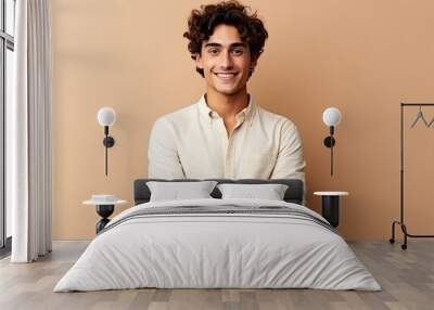 Portrait of a handsome young man with curly hair smiling at camera isolated over beige background, Happy young man. Portrait of handsome young man in casual shirt keeping arms crossed, AI Generated Wall mural