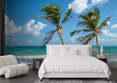 Two tall palm trees blowing in the wind on a sandy beach, Palm trees swaying in the ocean breeze Wall mural