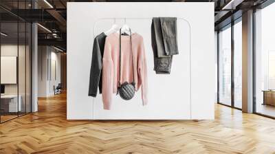 Female clothes in pastel pink and gray color on hanger on white background.  Jumper, shirt, jeans and bag. Spring/autumn outfit. Minimal concept. Wall mural