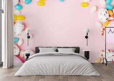 stylish frame made of easter candy chocolate eggs and jellybean on pink background Wall mural