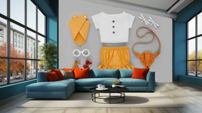 White shirt, orange shorts with kids handbag and sunglasses. Set of  baby clothes and accessories for summer vacation on  gray background. Fashion childs outfit. Flat lay, top view Wall mural