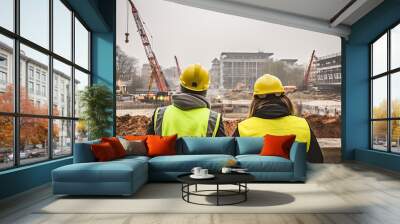 Rear shot of two engineers working on construction with helmet Wall mural