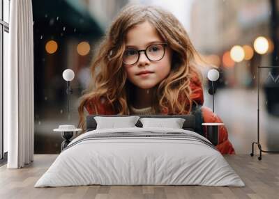 Portrait of a cute little girl in a red coat and glasses on the background of the city. Wall mural