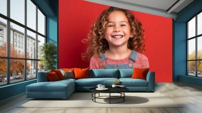 Portrait of a cute little girl with curly hair on a red background Wall mural