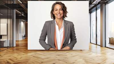 Portrait of a smiling business woman standing with hands in pockets against white background Wall mural