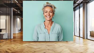 Portrait of a smiling middle-aged woman standing against turquoise background Wall mural