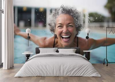 Portrait of happy senior woman smiling at camera in swimming pool at leisure centre Wall mural