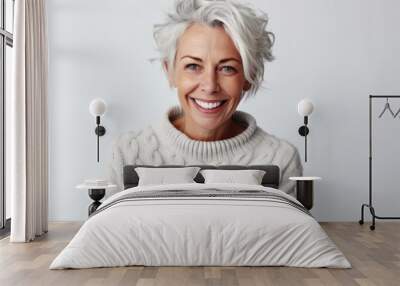 Portrait of smiling mature woman in sweater looking at camera over white background Wall mural