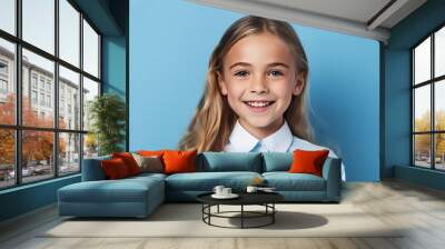 smiling little girl looking at camera on blue background with copy space Wall mural