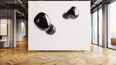   Two black earphones sit side-by-side on a white background adjacent to a white wall Wall mural