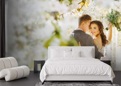 Amazing smiling wedding couple. Pretty bride and stylish groom posing and kisses. Flowery Romantic moment. Wall mural