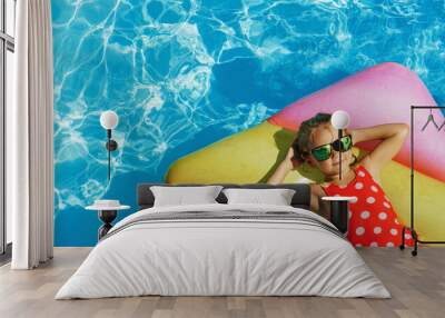 Child in swimming pool. Having fun on vacation at the hotel pool. Colorful vacation concept. Wall mural