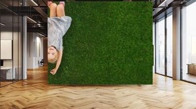 children lying on the green grass in the Park. The interaction of the children Wall mural