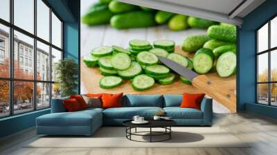 Whole and sliced fresh cucumbers on a cutting board on a light wooden background, selective focus. Wall mural