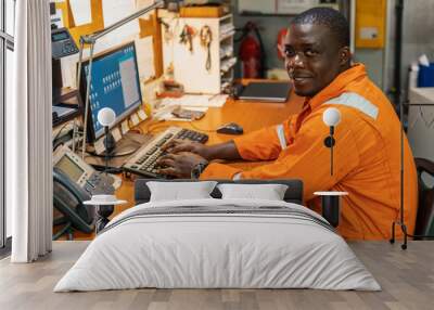 african marine engineer officer in engine control room ecr. seamen's work. he works at the computer Wall mural