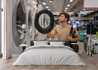 male shopper looking inside washing machine Wall mural