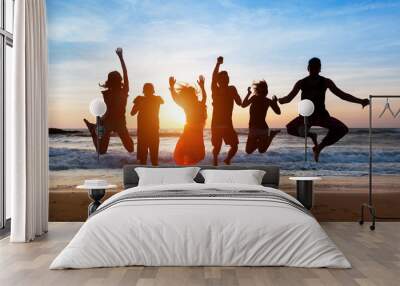 Six people jumping on beach at sunset. Wall mural