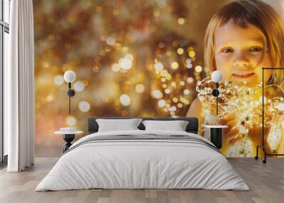 little girl with christmas lights looks at the camera Wall mural