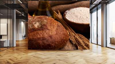 Loaf of bread on a wooden background, food closeup. Against the background of flour and vegetable oil with eggs. Vertical orientation Wall mural