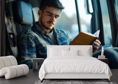 Man reading book in vehicle, focused and calm Wall mural