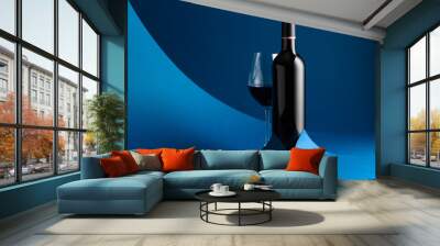 Bottle and glass of red wine on a blue background. Wall mural