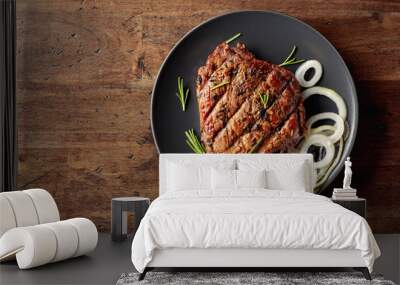 Grilled ribeye beef steak with rosemary and marinated onion on a black plate. Wall mural