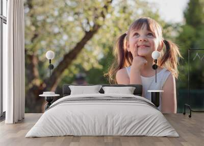 Happy little girl dreaming in the garden. Wall mural