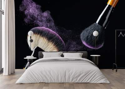 Makeup concept with a  professional makeup brushes with glowing purple eye shadow isolated on black background. Wall mural