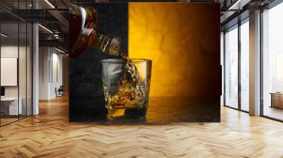 Pouring whiskey from a bottle into a glass. Wall mural