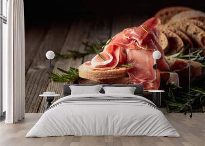 Prosciutto with bread and rosemary on an old wooden table. Wall mural