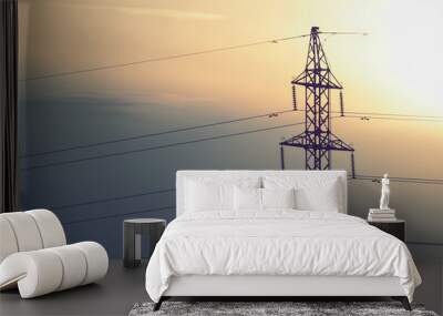 Overhead electrical power lines on a transmission tower against clear sky background. Electric energy distribution concept. High voltage pylons silhouette. Wall mural