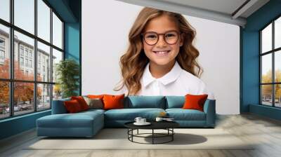 Portrait of a cute little girl wearing glasses and smiling at the camera Wall mural