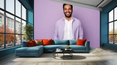 Portrait of a handsome young arabic man looking at camera and smiling while standing against purple background Wall mural