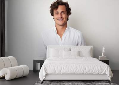 Portrait of a handsome young man smiling at the camera while standing against white background Wall mural