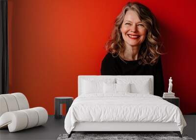 Portrait of a happy middle aged woman smiling and looking at camera on a red background Wall mural