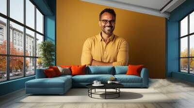 Portrait of a smiling Indian man with glasses on a yellow background Wall mural