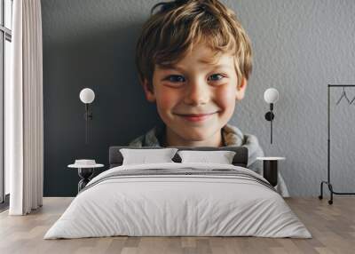 Portrait of a smiling little boy on a gray wall background. Wall mural