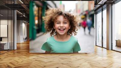 Portrait of a smiling little girl with curly hair on the street Wall mural