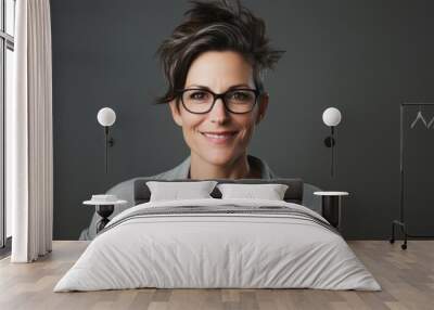 Portrait of smiling businesswoman with eyeglasses on grey background Wall mural