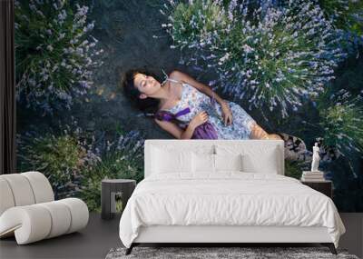 Young slim fair-skinned girl brunette beautiful lies in lavender field. Top view. Wall mural