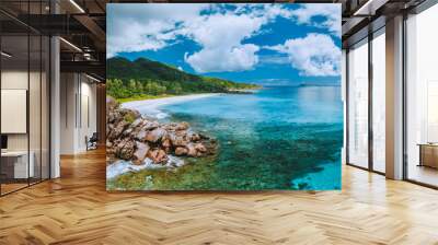 Aerial panoramic view of impressive Grand Anse beach on La Digue island in Seychelles. Granite boulders and turquoise ocean lagoon with white clouds above Wall mural