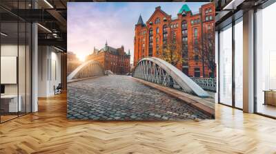 Arch bridge over alster canals with cobbled road in historical Speicherstadt of Hamburg, Germany, Europe. Scenic view of red brick building lit by golden sunset light Wall mural