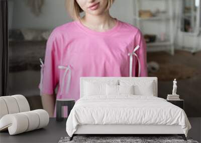 young beautiful woman posing in pink t-shirt in studio, sitting on the bench in white skirt near window Wall mural