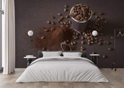 Coffee beans and ground powder on brown background. Wall mural