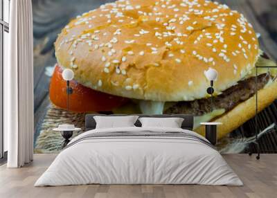 Close-up of a delicious fresh homemade burger with lettuce, cheese, onions and tomatoes on a wooden table, the concept of a mouth-watering meal Wall mural