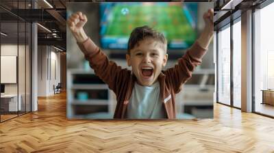 Excited boy cheering for soccer win in front of TV at home Wall mural