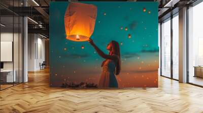 Young woman releasing a sky lantern into the night sky Wall mural