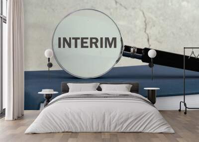 A word INTERIM through a magnifying glass on the wall. Concept photo Wall mural